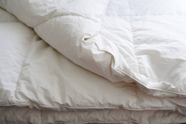 Close-up of a neatly folded, white down comforter, illustrating how to care for and wash down-filled items.