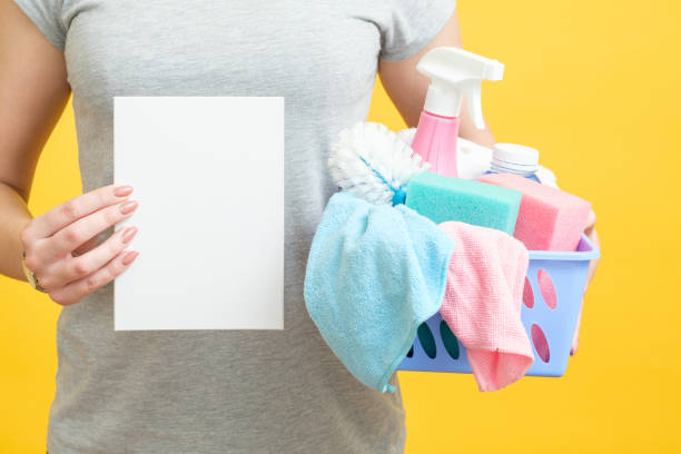 Person holding a cleaning supplies basket and a checklist, ready for spring cleaning.